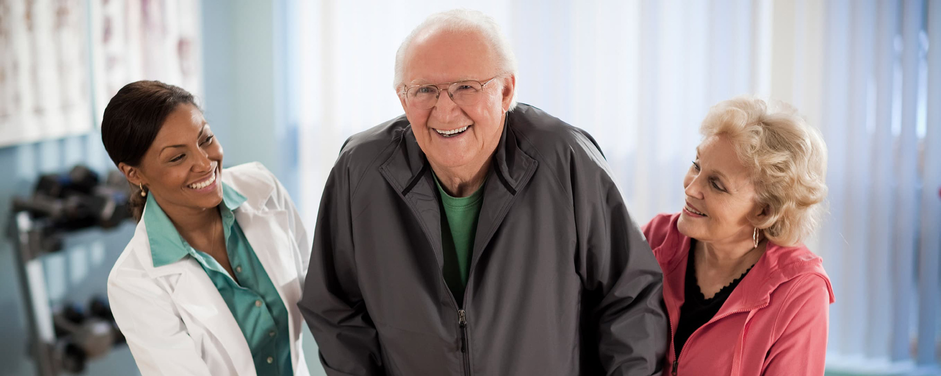 Elderly man with a nurse and elderly woman in fitness room
